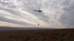 Helicopter flying over Moors for the Future site with restoration materials