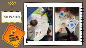 'Work in progress' sign with a digger on it next to two photographs of children drawing on large sheets of paper