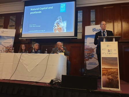 A man at a lectern speaking at the 2019 IUCN UK Peatland Programme conference