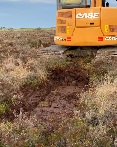 Close up of digger installing a peat dam